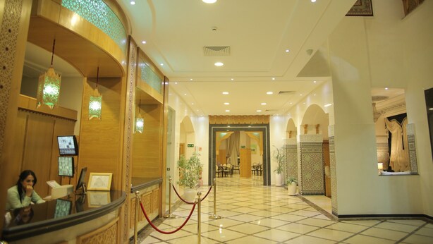Una hall d'albergo con reception, area salotto e elementi decorativi.