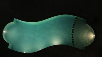 Un objeto curvado de color aguamarina con hendiduras circulares y pequeñas luces a lo largo del borde.