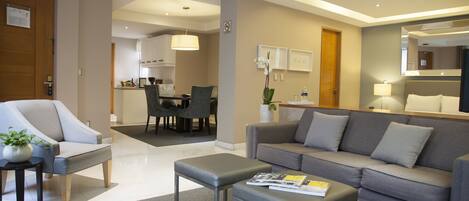 A modern living room with a grey sofa, a grey armchair, and a small table with a magazine.