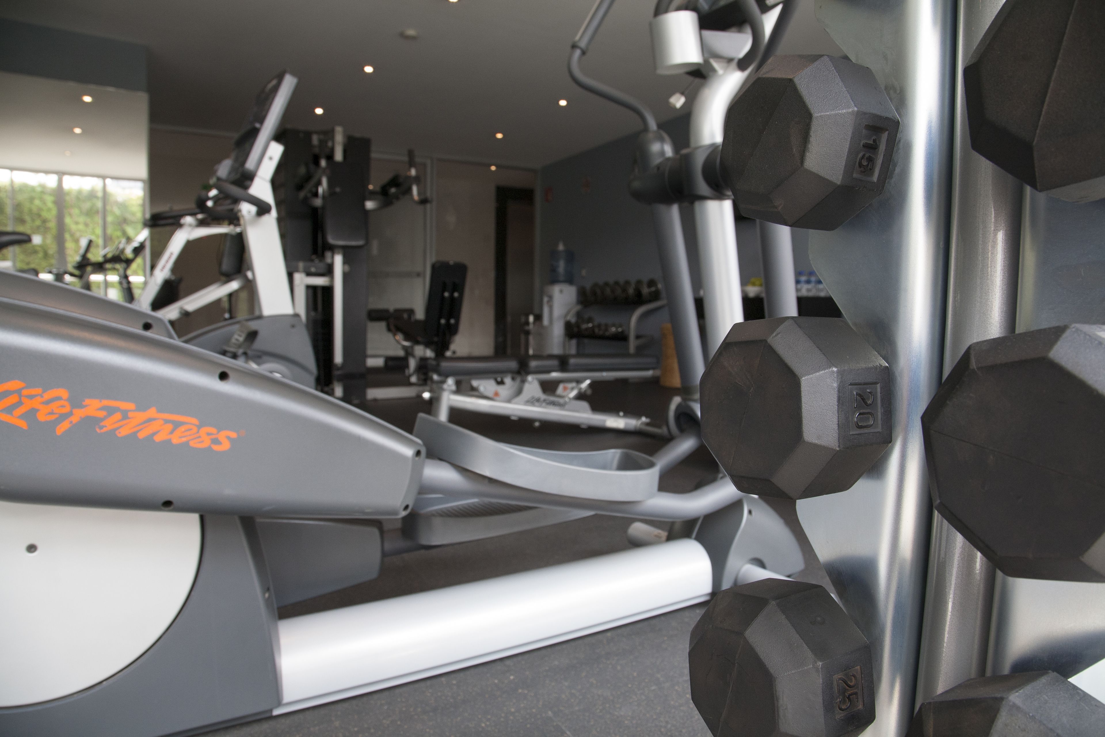 Una palestra con attrezzature per esercizi, tra cui tapis roulant e manubri.
