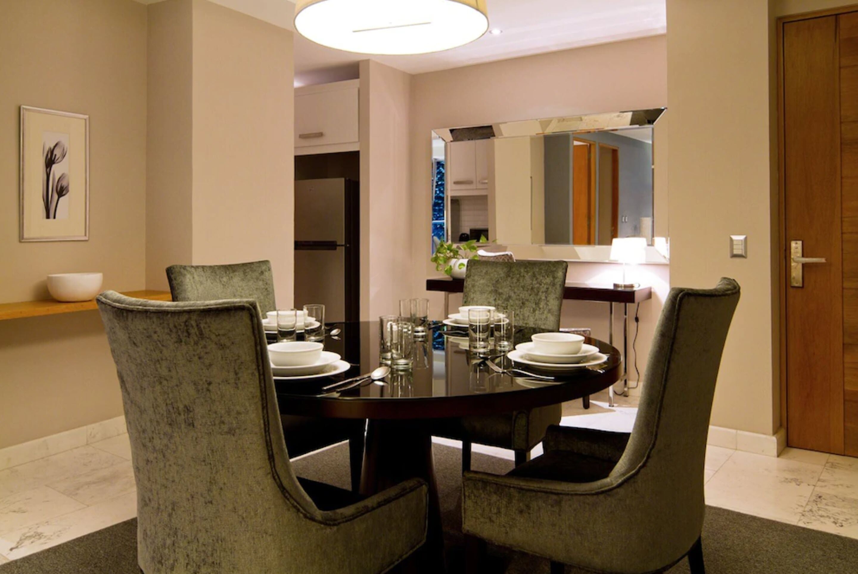 Un coin repas avec une table ronde dressée pour quatre personnes, entourée de chaises rembourrées.