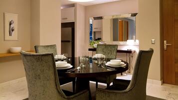 Un coin repas avec une table ronde dressée pour quatre personnes, entourée de chaises rembourrées.