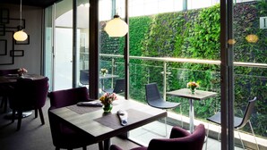 Un comedor moderno con una mesa de madera, sillas moradas y vistas a una pared verde exuberante.