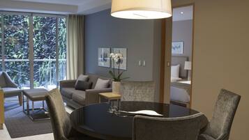 A modern dining area with a round table, four upholstered chairs, and a hanging light fixture.