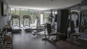 Un gimnasio con cintas de correr, máquinas de pesas y un espejo.