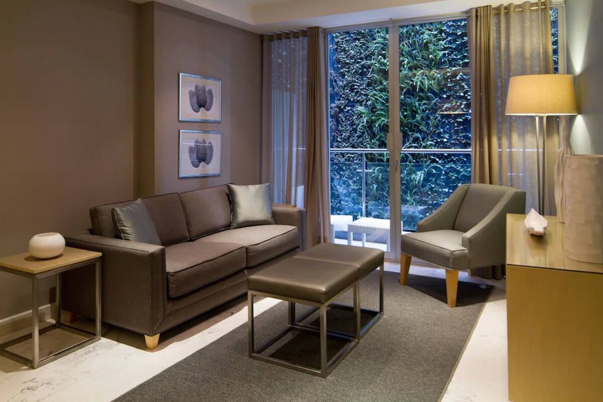 Una sala de estar moderna con sofá, sillón, mesa de centro y mesitas auxiliares.