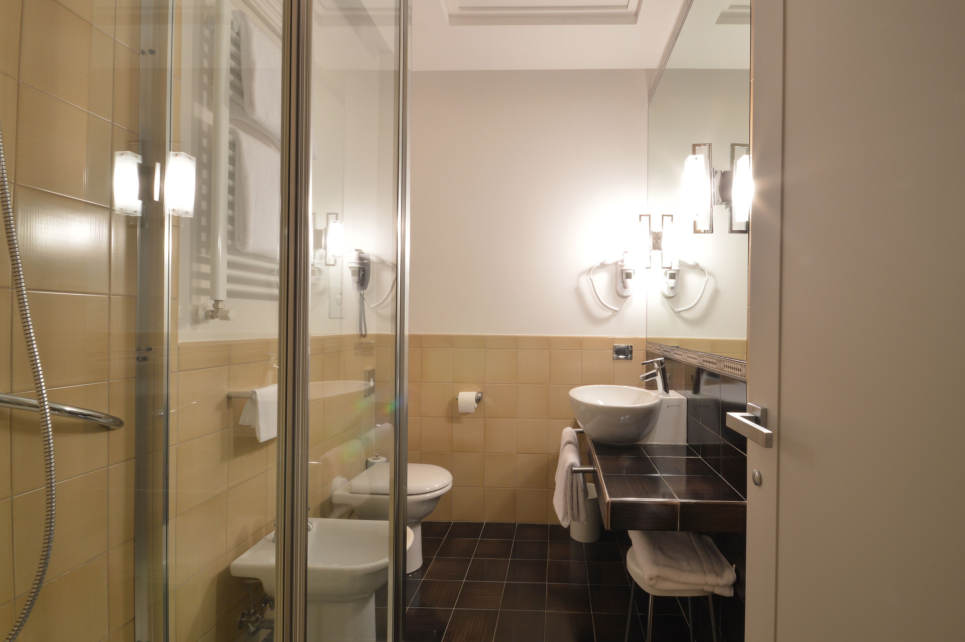 A bathroom with a glass-enclosed shower, a toilet, a sink, and a mirror.