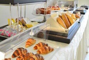 Een buffet met diverse gebakken producten, waaronder brood, gebak en desserts.