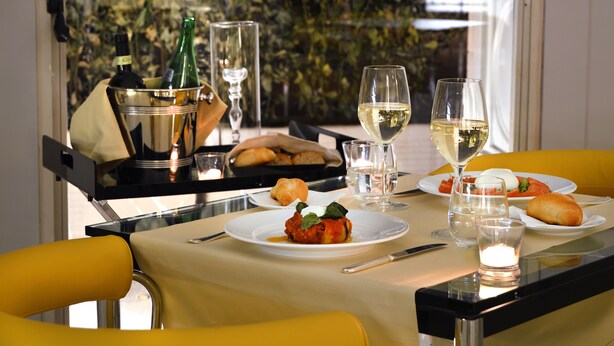 A dining table set with plates of food, glasses, and a bottle of wine. - Hotel Palazzo Esedra (Naples)