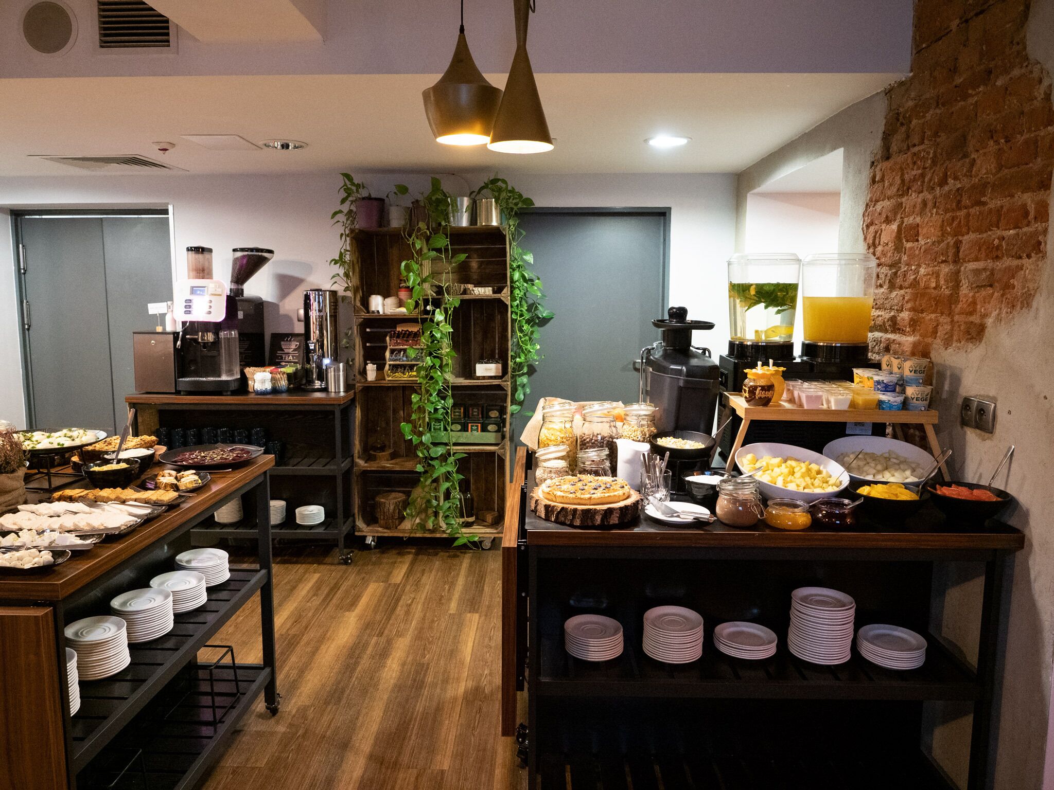 Buffet de café da manhã com diversos alimentos, um espaço para café e um bar de sucos.