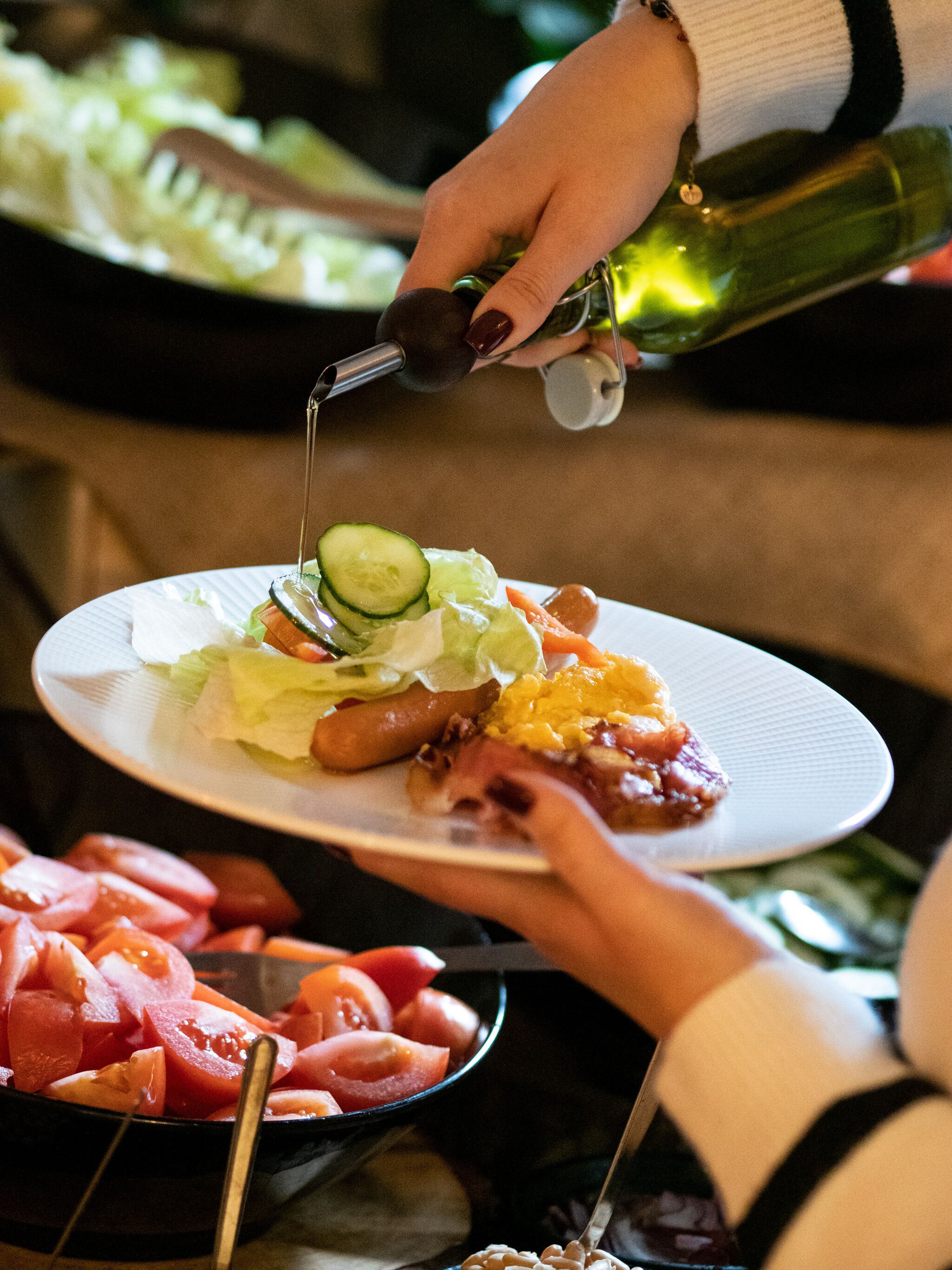A person pouring a clear liquid from a green bottle onto a plate with food.