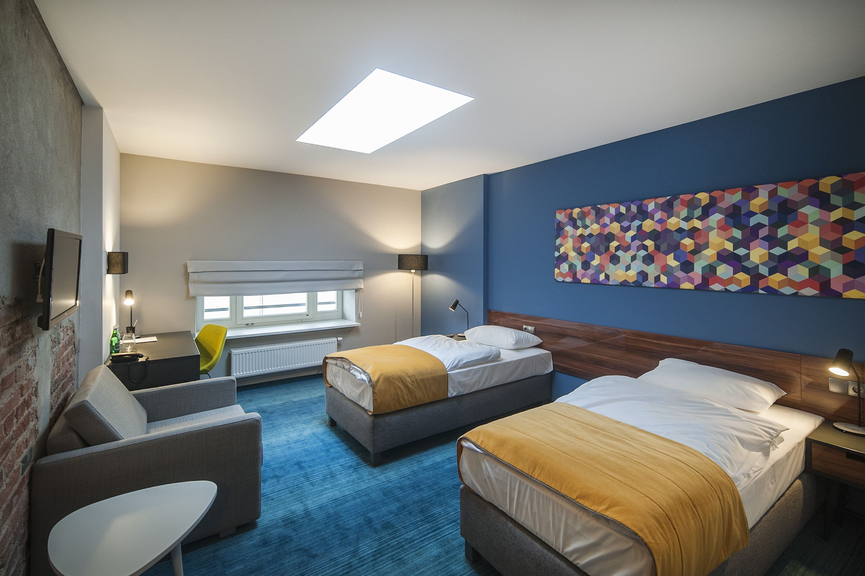 A hotel room with two beds, a sofa, a table, and a window.