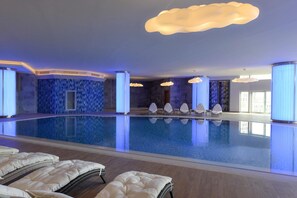 Una amplia piscina cubierta con sillones de descanso y un diseño de techo moderno.
