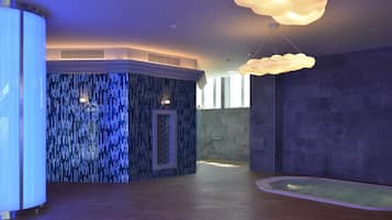Un moderno espacio de spa con una pared de piedra, suelo de madera y una bañera grande.