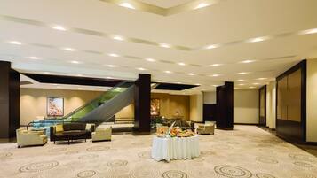 A spacious lobby with a central seating area, a buffet table, and an escalator.