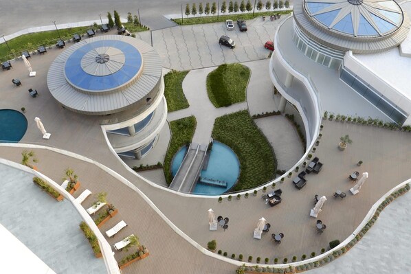 Un hotel moderno con un patio central circular, zonas de estar al aire libre y una piscina.