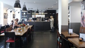 A modern restaurant with a central bar area, multiple dining tables, and a variety of seating options. - The Z Hotel Victoria (London)