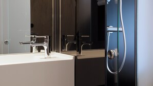 A modern bathroom with a white sink, chrome faucets, and a glass-enclosed shower. - The Z Hotel Victoria (London)