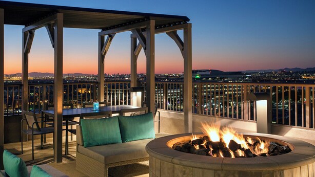 Eine Außenpatio mit Feuerstelle, Sitzgelegenheiten und Blick auf die Stadt bei Dämmerung.