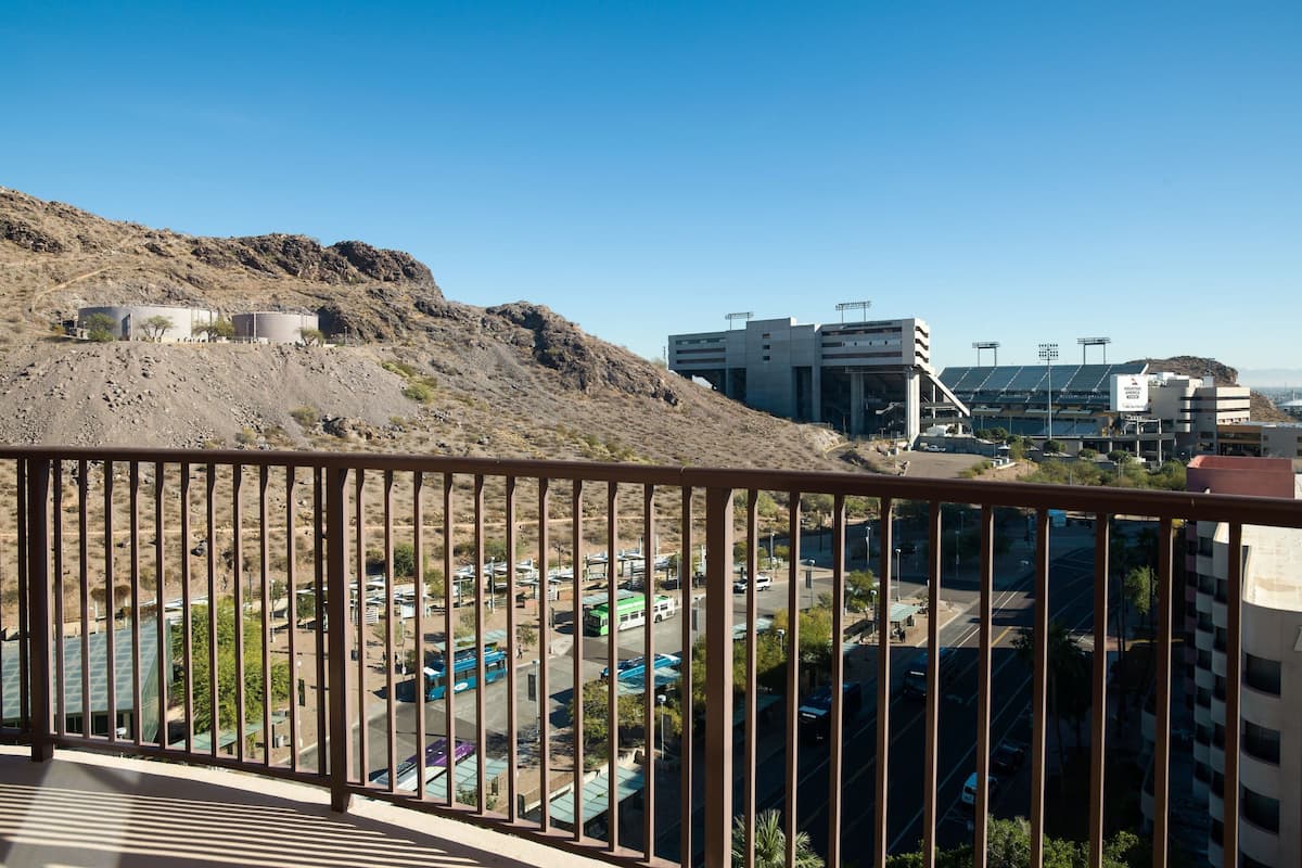 Une vue depuis un balcon donnant sur un parking, un paysage vallonné et des bâtiments modernes dotés de panneaux solaires.