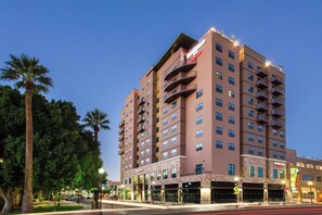 A multi-story hotel with balconies, a ground-level restaurant, and a well-lit facade.