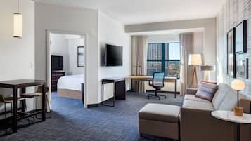 Ein Hotelzimmer mit Bett, Schreibtisch, Stuhl, Sofa und Fernseher.