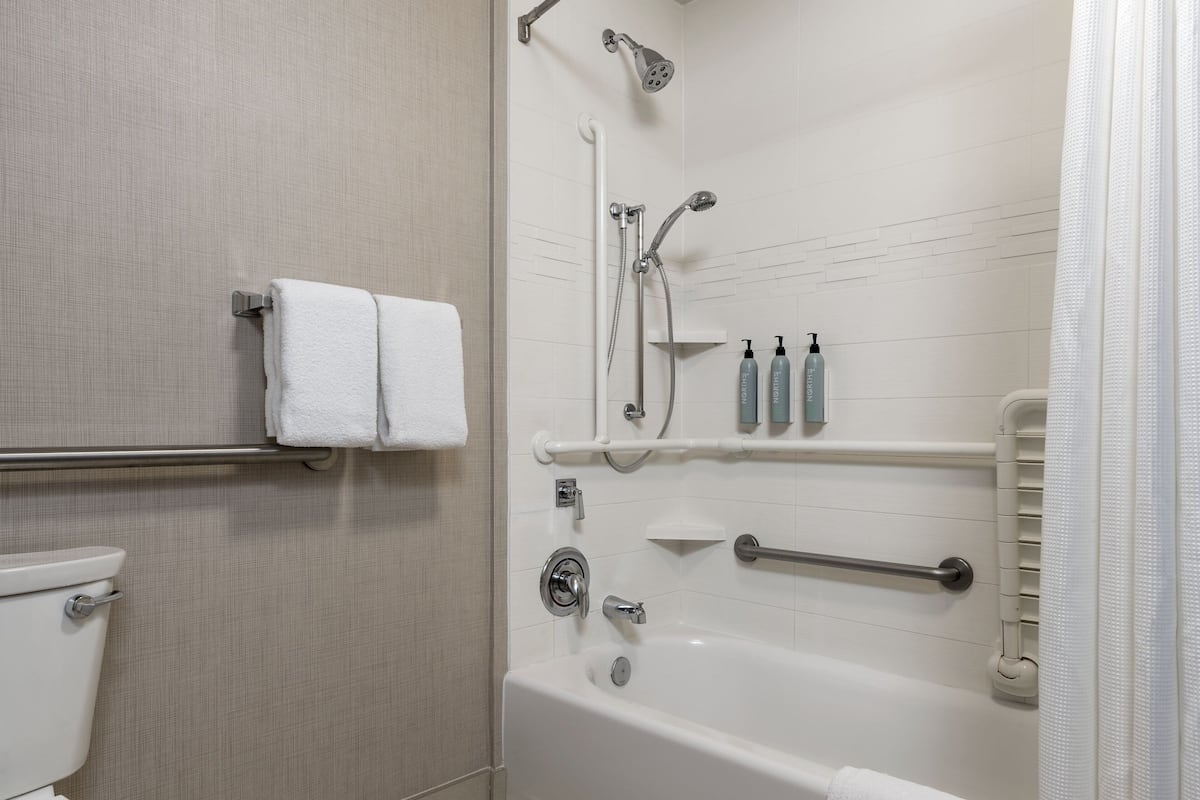 Une salle de bain équipée de toilettes, d’une baignoire, d’une douche et d’un porte-serviettes.