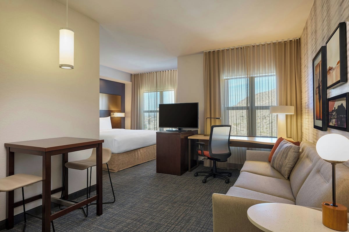 Une chambre d’hôtel comprenant un lit, un bureau avec un ordinateur, une chaise, un canapé, une télévision et une lampe.