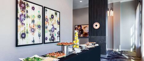 Montaje de bufé con diversos alimentos y un diseño interior moderno que incluye arte abstracto en las paredes.