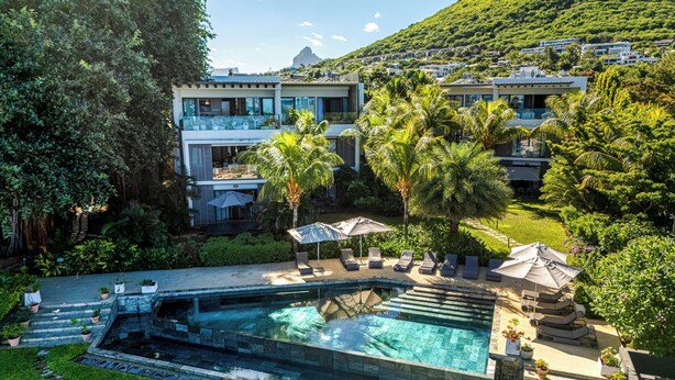 Un resort moderno con piscina, sillones de descanso y un jardín exuberante.