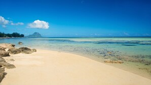 Una playa con agua turquesa cristalina, una orilla de arena y una montaña distante.