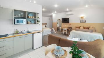A modern hotel room with a kitchenette, a dining area, and a bed.