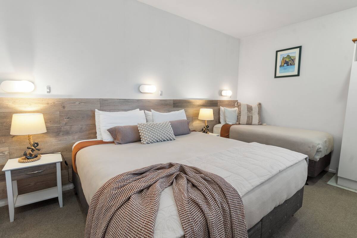 A bedroom with a large bed, two bedside tables with lamps, and a headboard with built-in lighting.
