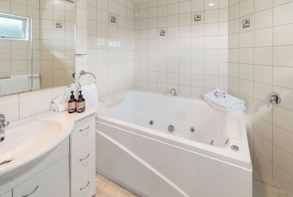 A modern bathroom with a white bathtub, a sink, and a mirror.