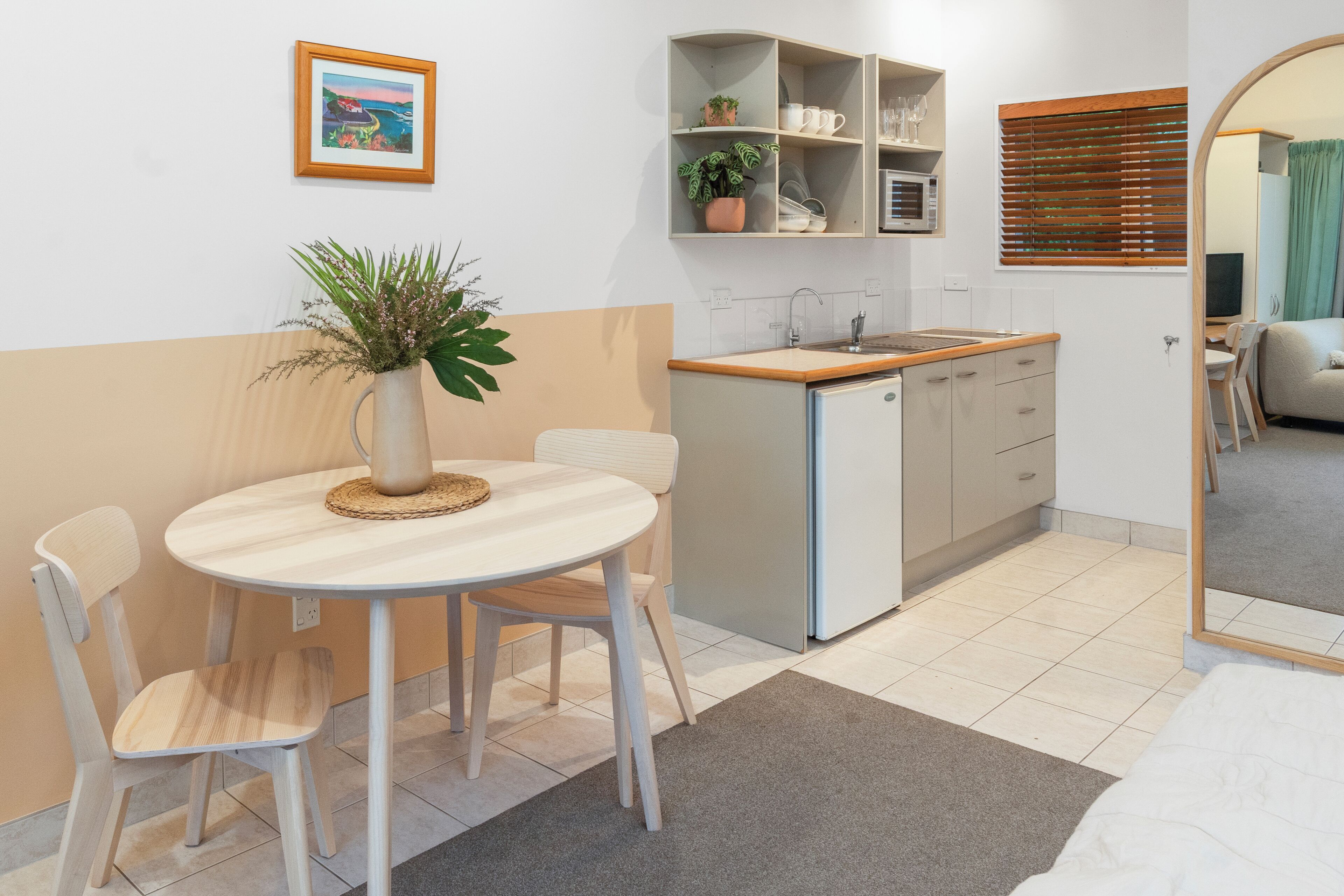 Une cuisine compacte comprenant un évier, des placards et un petit coin repas avec une table et des chaises.