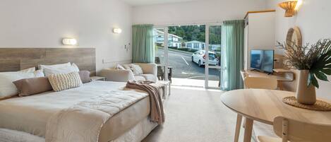 Habitación de hotel con cama, escritorio, silla, televisión y vista a la calle.
