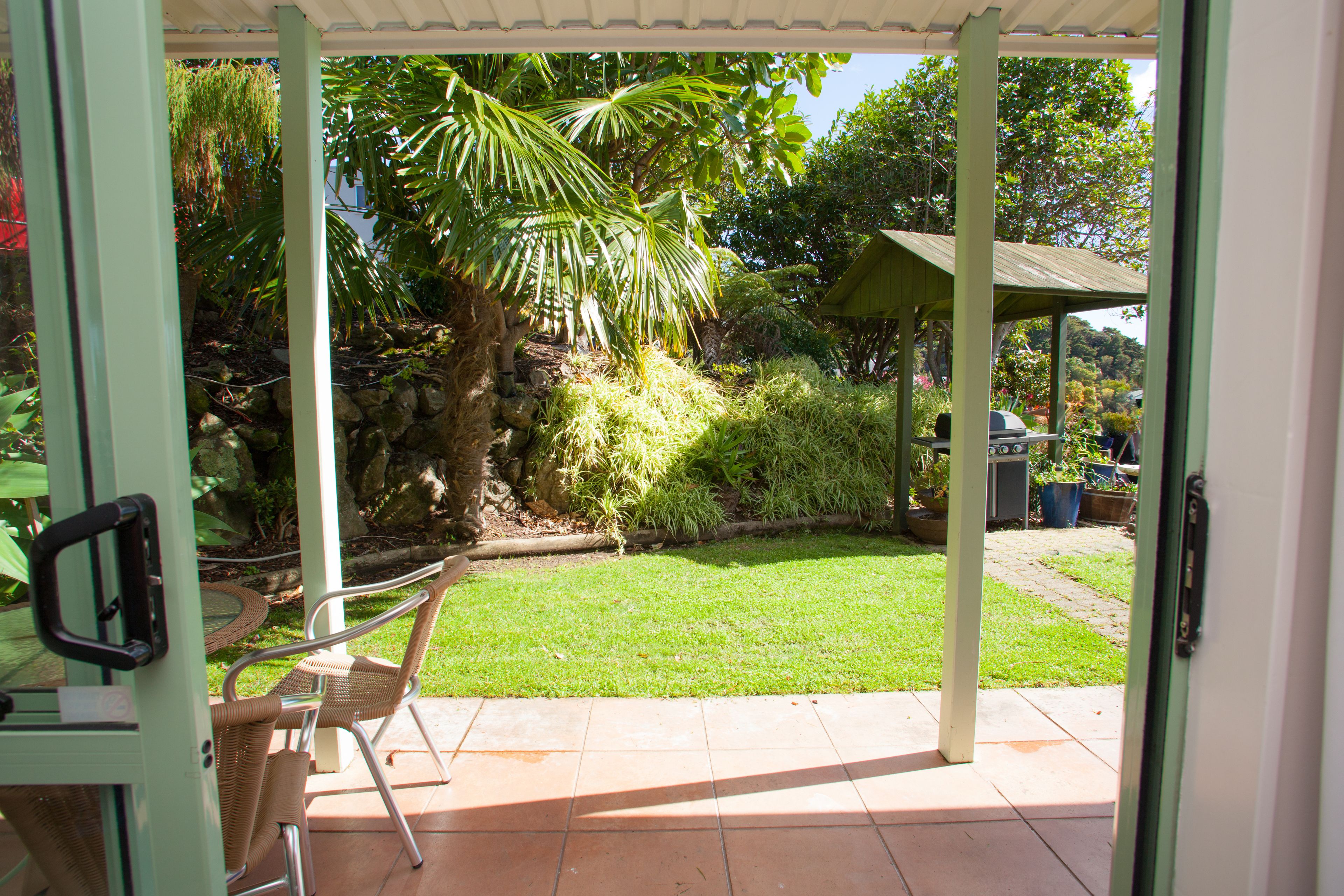 A patio with a covered seating area, a lawn, and a stone wall.