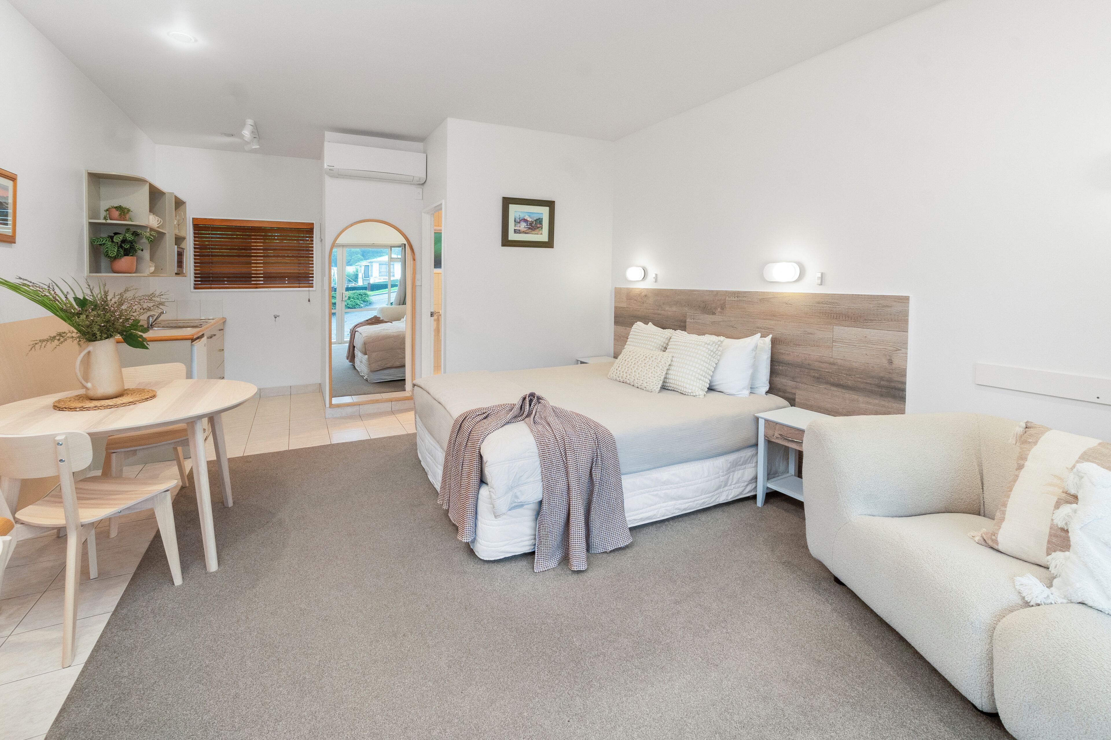 A modern bedroom with a bed, bedside table, and a desk with a chair.