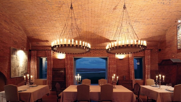 Comedor con paredes de ladrillo, candelabros y vistas al paisaje.