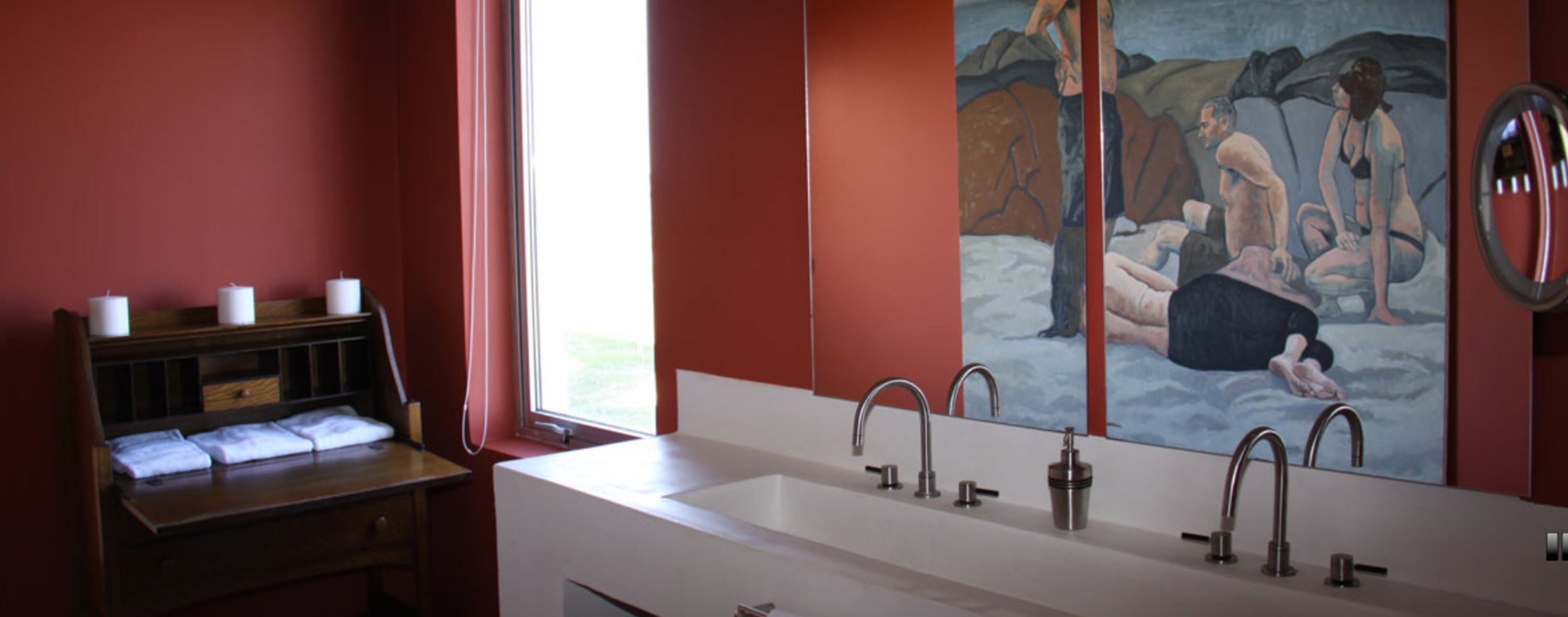 A bathroom with a large mirror, a sink with three faucets, and a painting of a nude couple on the wall.