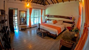 A spacious bedroom with a large bed, wooden headboard, and a wooden floor. - Suchipakari Jungle Lodge (Misahualli)