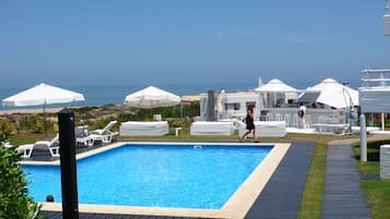 Una piscina al aire libre de temporada, sombrillas