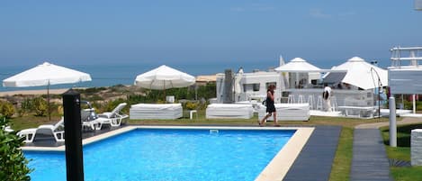 Una piscina al aire libre de temporada, sombrillas