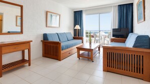 Un salon moderne avec un canapé, une table basse et un téléviseur. Il y a un balcon avec vue.