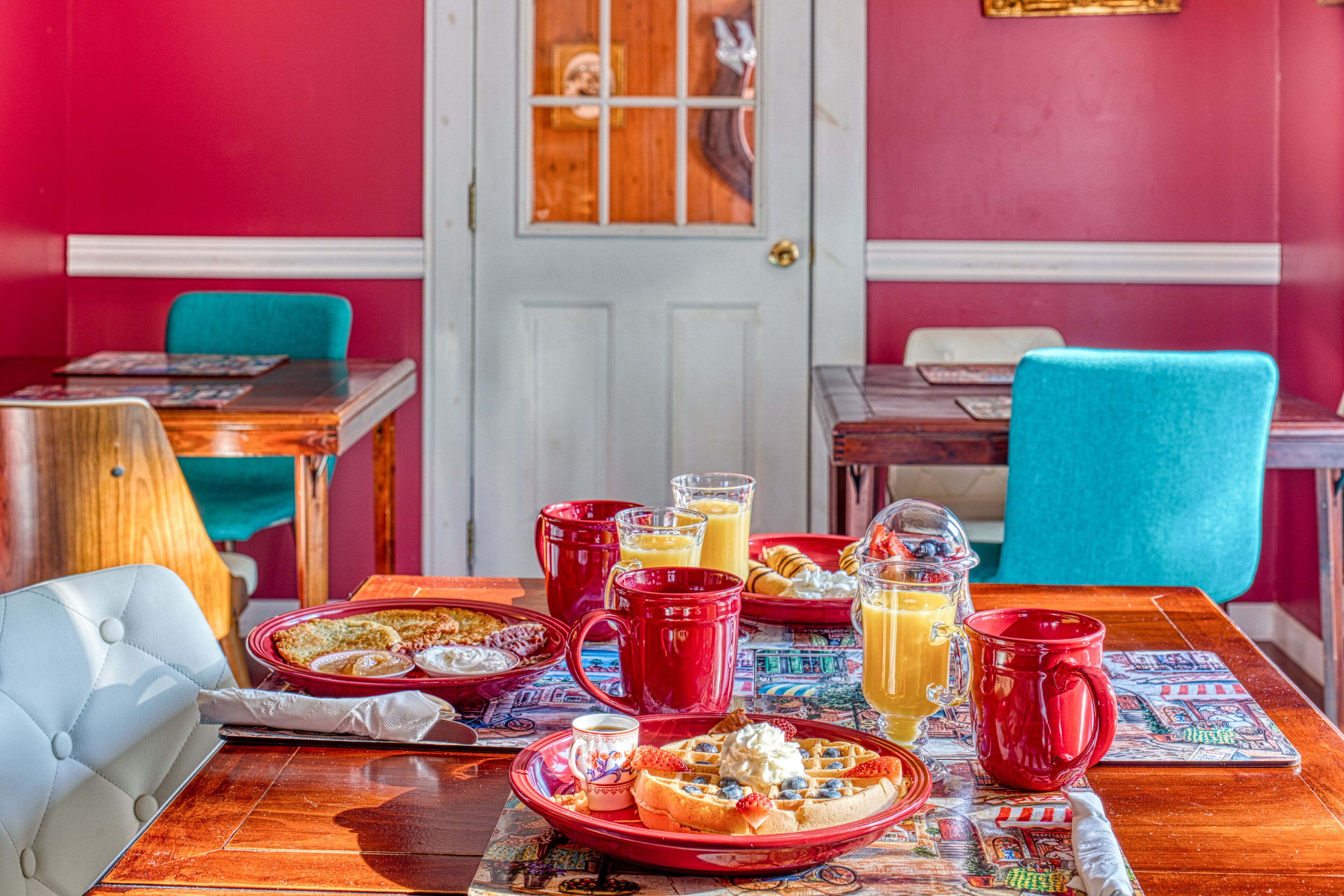 Ein Frühstückstisch mit verschiedenen Speisen, darunter Waffeln, Pfannkuchen und einer Obstschale.