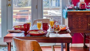 A dining table set with breakfast items, a red mug, and a glass of orange juice. - Mountain Treasure B&B (Maplecrest)