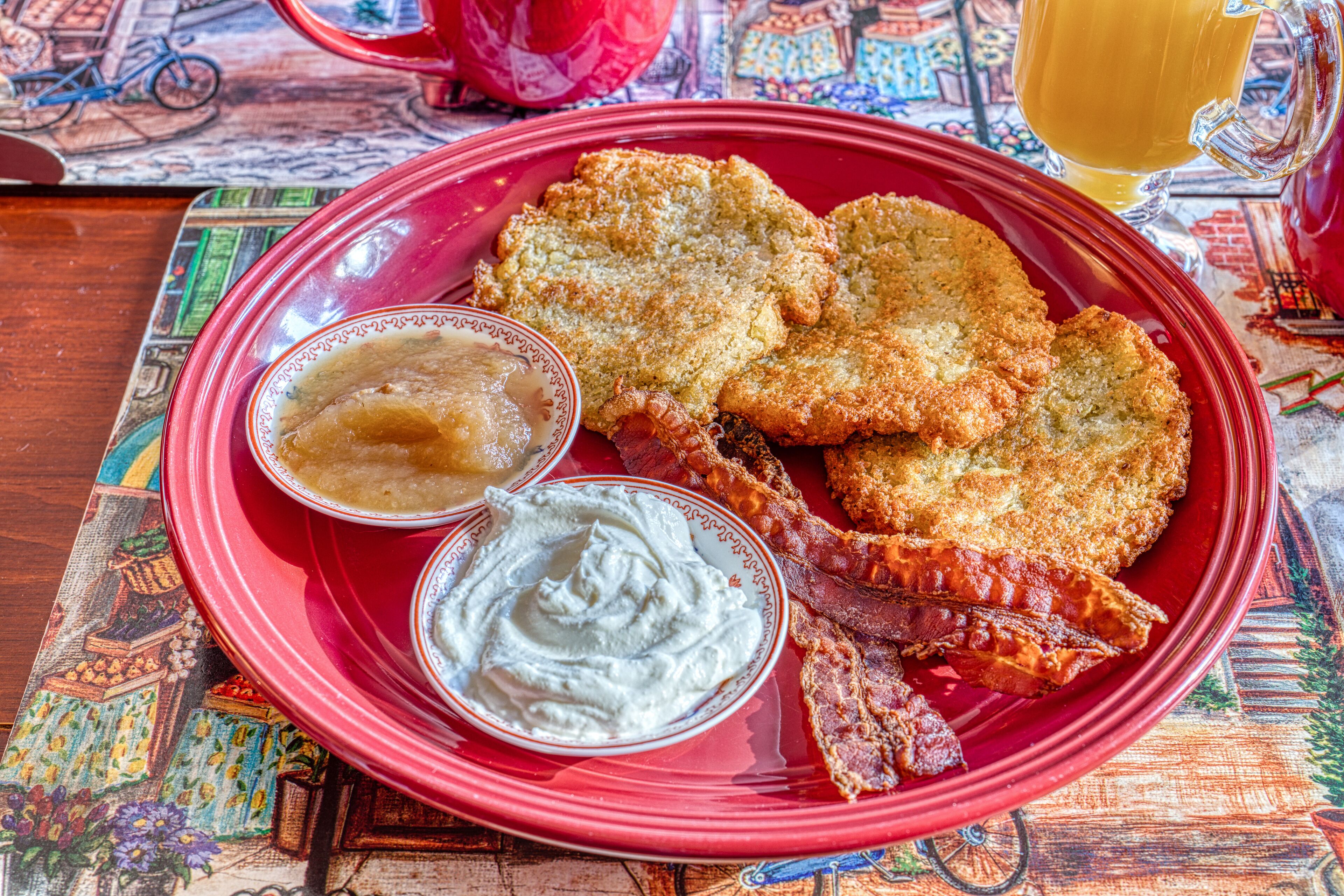 Une assiette rouge contenant des aliments frits et deux sauces pour tremper.