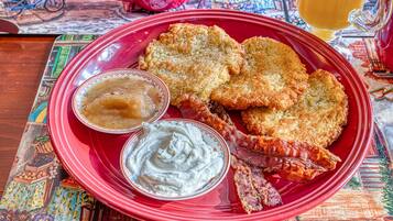 Une assiette rouge contenant des aliments frits et deux sauces pour tremper.
