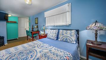 A bedroom with a bed, a desk, a chair, and a lamp.