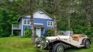 A vintage car parked in front of a house surrounded by trees. - Mountain Treasure B&B (Maplecrest)